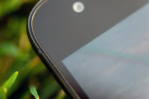 Smartphone frontal camera and screen close-up photo on green grass Photos