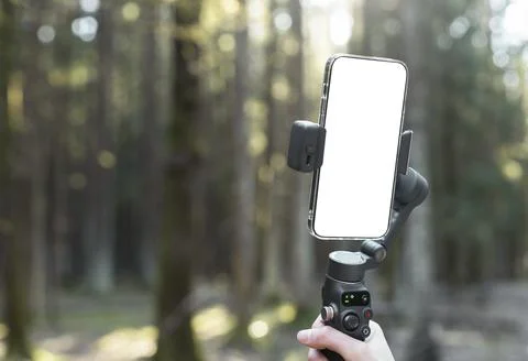 Smartphone gimbal held in a forest. Mobile videography gear with blurred Foto stock