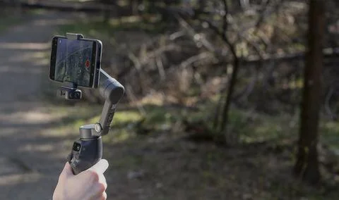 Smartphone on a gimbal stabilizer in a forest. Handheld mobile filming gear Stock Photos
