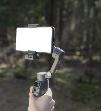 Smartphone on a gimbal stabilizer in a forest. Mobile filming setup with Stock Photos