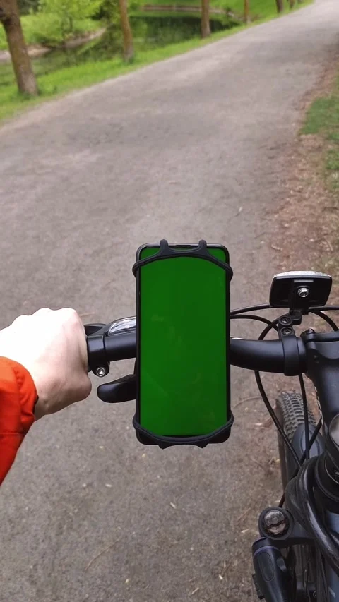 A smartphone with a green screen is attached to the handlebar of the bike. A Stock Footage 309404419