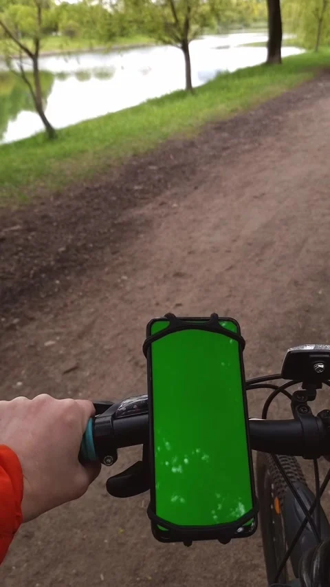A smartphone with a green screen is attached to the handlebars of the bike, a Stock Footage 310117786