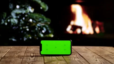 Smartphone with a green screen chroma key screen against a cozy fireplace and Stock Footage 320586424