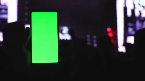 A smartphone with a green screen chromakey on the background of a concert screen Stock Footage