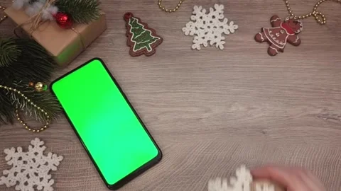 A smartphone with a green screen, a gift and Christmas decorations, a hand Stock Footage 319778916