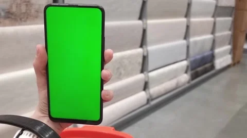 Smartphone with green screen in hand close-up, in a hardware store, in the Stock Footage 282390432