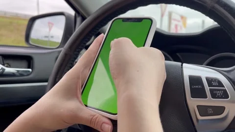 Smartphone green screen in the hands of a driver driving a car, woman holdi.. Video stock 252020705