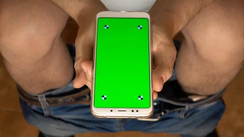A smartphone with a green screen in the hands of a man while he is sitting in Stock Footage 88540567