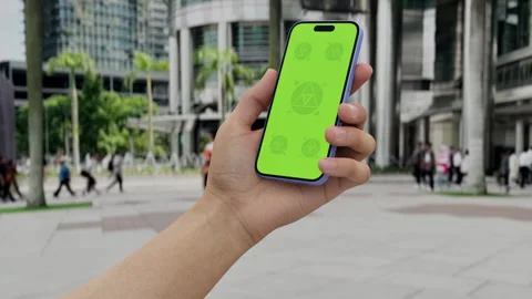 Smartphone with green screen held in hand in an urban cityscape with palm trees Stock Footage 296943437