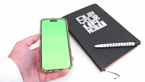 Smartphone with green screen. Iphone 14 pro. Сhromakey.  White Table Stock Footage 249757317