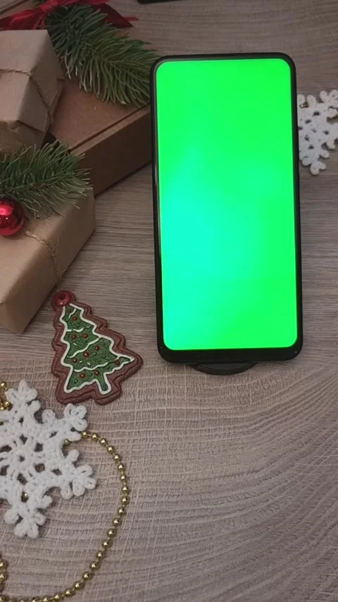 A smartphone with a green screen lies vertically on a wooden table next to gifts Stock Footage 310118112