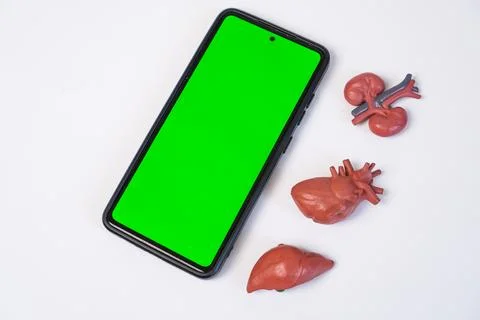 A smartphone a green screen mockup placed diagonally next to three miniatur.. Stock Photos