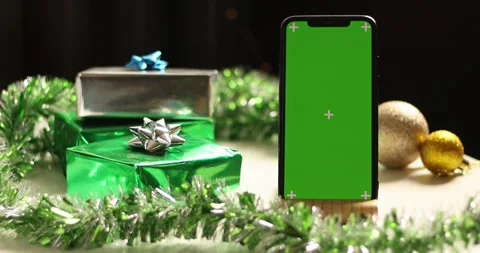 Smartphone with green screen surrounded by festive Christmas gifts and Stock Footage 339073198