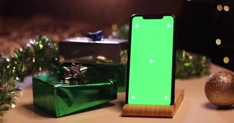 Smartphone with green screen on a table with Christmas gifts and lights Stock Footage 339072220