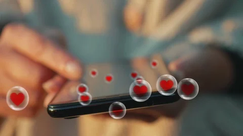 Smartphone in hand accessing popular content. Swirl of likes pouring. 스톡 동영상 118535212