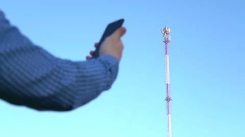 Smartphone in hand against the background of the telecommunication tower Stock Footage 152474046