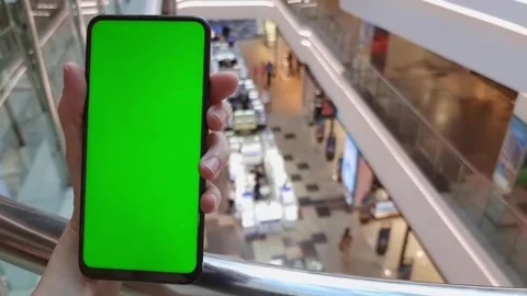 Smartphone in hand with green screen, close-up, on the background of a shopping Stock Footage 281788478