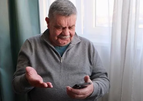 The smartphone is in the hands of an elderly man Stock Photos