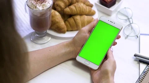Smartphone in the hands of a green screen in a cafe, smart phone with chroma key Video stock 84076508