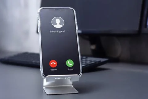 Smartphone with incoming call on desktop on computer background. Stock Photos