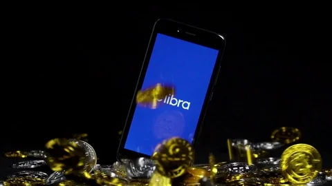 Smartphone with Libra logo and Cryptocurrency digital golden coins falling down Video stock 111743202