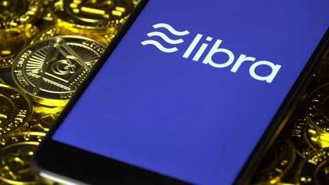 Smartphone with Libra logo on the screen and Cryptocurrency digital golden coins Stock Footage 111743336