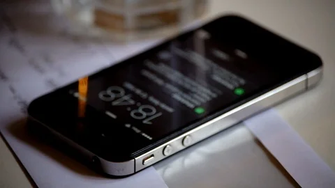 A smartphone with a lit screen showing notifications goes black. Stock Footage