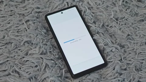 Smartphone lying on carpet screen displaying file download progress status Stock Footage 341569467