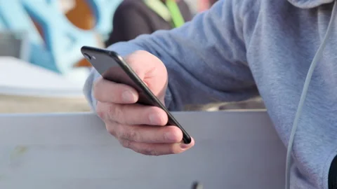 Smartphone in a man's hand in an open space. A person is typing and reading on a Stock Footage 229866843