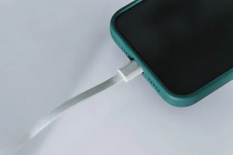 Smartphone in Mint Green Case Charging with White USB Cable Stock-Fotos