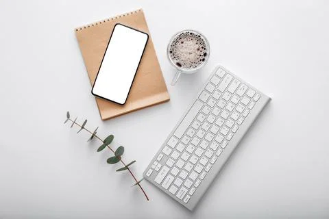 Smartphone mock up with note keyboard coffee cup green plant on white work space Stock-Fotos
