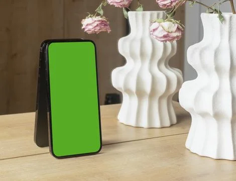 Smartphone mockup with a blank white screen leans on a wooden table near de.. Stock-Fotos