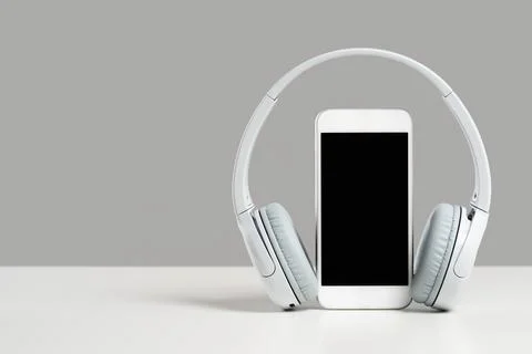 Smartphone mockup display with grey wireless headphones on gray background Stock Photos