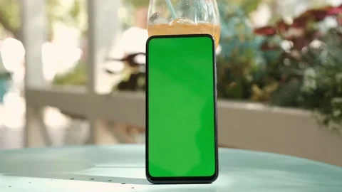 Smartphone with mockup green screen standing on a table in a cafe Stock-Footage 164220672