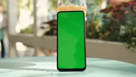 Smartphone with mockup green screen standing on a table in a cafe Stock Footage 165969301