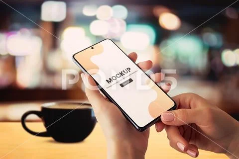 Smartphone mockup in hands with coffee mug on table PSDテンプレート