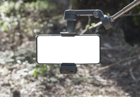 Smartphone mounted on a gimbal stabilizer in a forest. Blank screen mobile Stock Photos