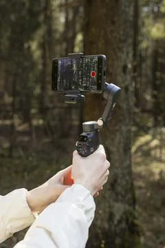 Smartphone mounted on a gimbal stabilizer in a forest. Hands hold mobile fi.. Stock Photos