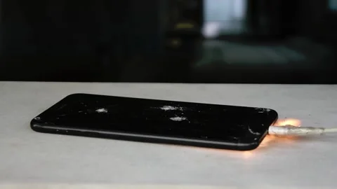 The smartphone overheats and ignites while charging the battery, flying sparks a Stock Footage 261519621
