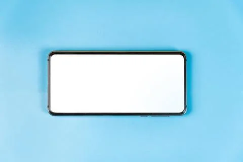 A smartphone with a place for an inscription on white lies on a blue table. Stock Photos