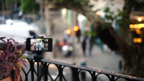 A smartphone placed on a tripod outside on a balcony films a scene Stock Footage 101346974