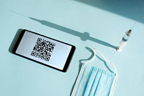 Smartphone with quar code of vaccination certificate on the screen, syringe and Stock Photos