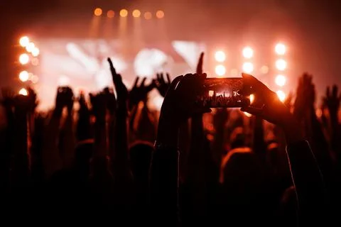 Smartphone Recording a Live Performance at a Red Lit Rock Concert Stock Photos