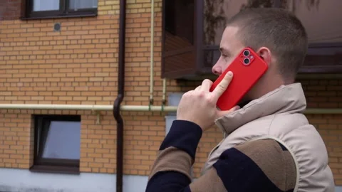Smartphone in a red case in the hand of a Caucasian guy who is walking around Stock Footage 287148726