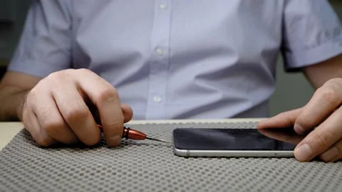 Smartphone repair maker repairs broken phone with broken screen, unscrews screws Stock Footage 137658873
