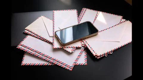 Smartphone resting on envelopes highlights intersection of digital and Stock Photos