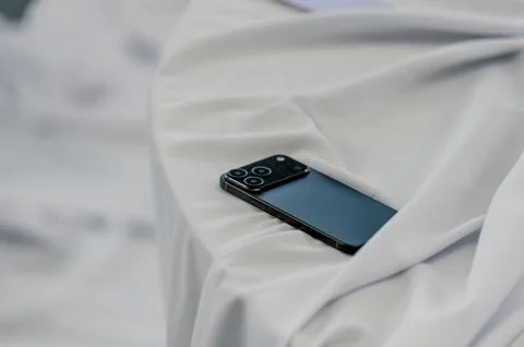 Smartphone resting on white fabric surface with soft draping Stock Photos