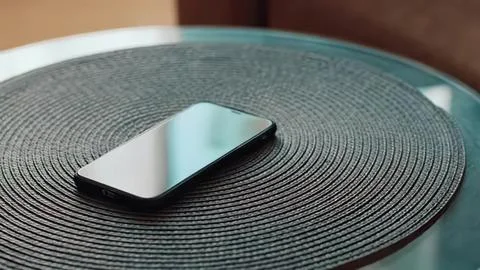 Smartphone on a round black textured surface Stock Photos