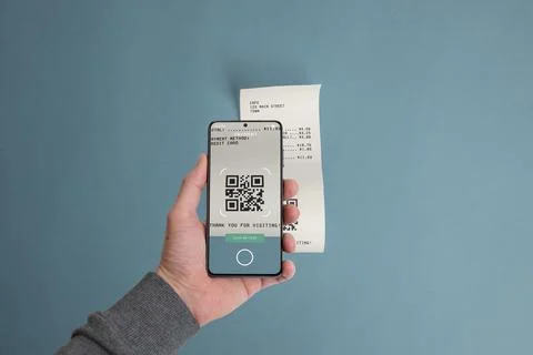 Smartphone scanning a QR code on a paper receipt placed on a table Stock Photos
