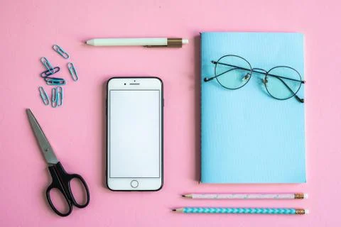 Smartphone, scissors, notebook with eyeglasses, clips, pen and pencils Foto stock